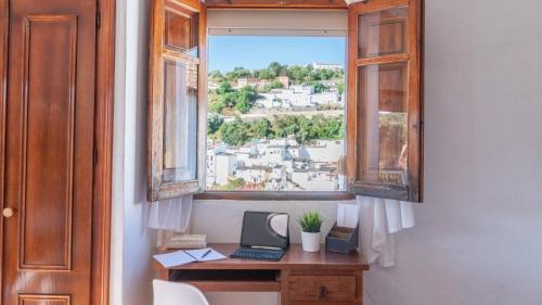 un ufficio con una finestra e un computer portatile su una scrivania di Los cortinales a Setenil