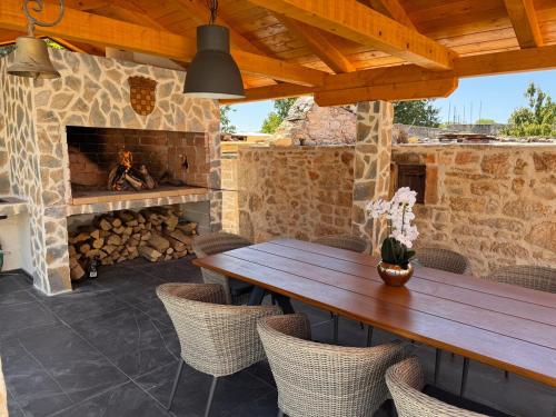 an outdoor patio with a wooden table and a fireplace at Villa Zvonimir in Suknovci
