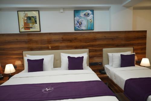 two beds in a hotel room with purple and white pillows at VOVO Boutique Hotel in Bengaluru