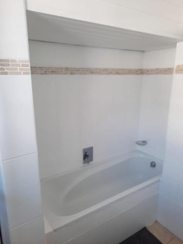 a bath tub in a bathroom with a white wall at Pips Place 203 in Strand