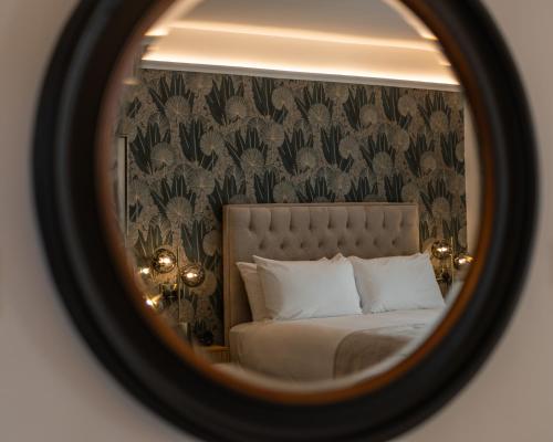a mirror reflecting a bed in a bedroom with a wallpaper at No 5 Rose Inn Street - Room 3 in Kilkenny