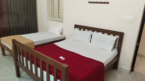two twin beds in a room with a red blanket at Rémi Villa White Town in Puducherry