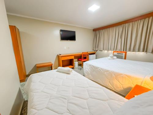 a hotel room with two beds and a television at Hotel Nacional Inn Campos do Jordão in Campos do Jordão