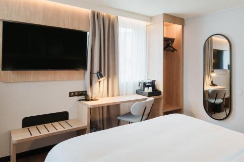 タッサン・ラ・ドゥミ・リュンヌにあるCampanile PRIME - Lyon Ouest Tassinの白いベッドと鏡のあるホテルの部屋