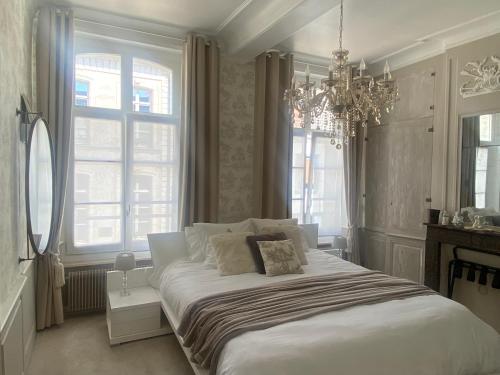 a bedroom with a large white bed with a chandelier at Aux remparts de Montreuil in Montreuil-sur-Mer