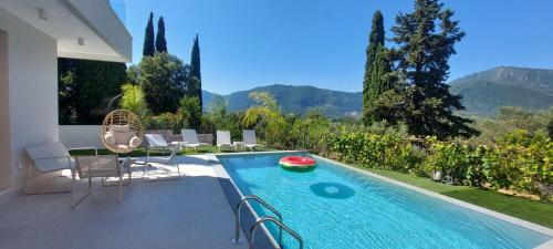 a swimming pool with chairs and a view of mountains at Villa Harmony Luxury Resort in Corfu Town