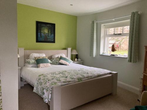 a bedroom with a bed with green walls and a window at Moorview Retreat, Dartmoor in Widecombe in the Moor