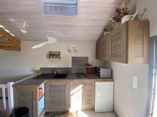 une cuisine avec des armoires en bois, un évier et un réfrigérateur dans l'établissement la gloriette, à Moncrabeau