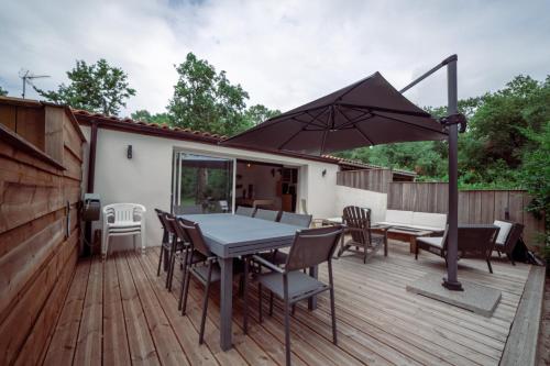 una terrazza con tavolo, sedie e ombrellone di Maison vu Lac en première ligne du lac de Lacanau avec terrain de tennis privatif a Lacanau