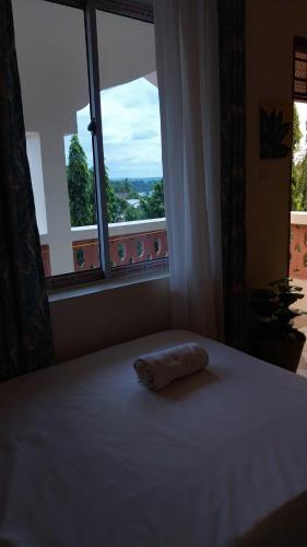 a bed with a pillow on it in front of a window at Makao in Kilifi