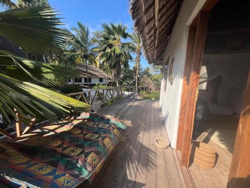 a porch of a house with palm trees and a building at Kimulimuli Ayurveda Spa Retreat in Kiganga