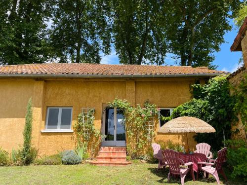 a house with chairs and a table and an umbrella at Le Petit Basket in Castex