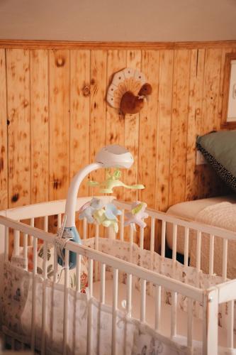 a baby crib in a room with wooden walls at Domaine du PIAOU "chambres & table d'hôte" in Le Val