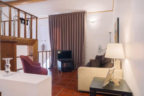 a living room with a couch and a tv at Apartamentos da Galé in Caloura