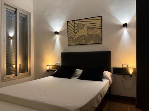 Un dormitorio con una cama con dos luces en la pared. en Loft Almagro, en Almagro