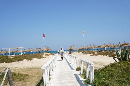 a man walking down a boardwalk to the beach at Sentido Marillia Resort & Spa in Hammamet