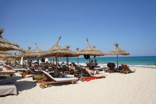 a group of people sitting on a beach with umbrellas at Sentido Marillia Resort & Spa in Hammamet