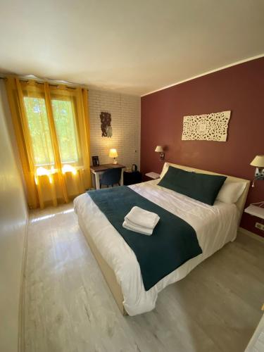 a bedroom with a large bed with two towels on it at Hôtel Beausoleil in Montélimar