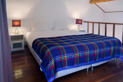 un letto con una coperta scozzese blu e due lampade di Apartamentos da Galé a Caloura