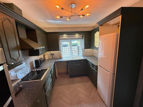 a kitchen with black cabinets and a white refrigerator at Winchelsea Lodge in Winchelsea