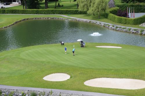 two people on a golf course with a pond at Schlosshotel Kitzbühel in Kitzbühel