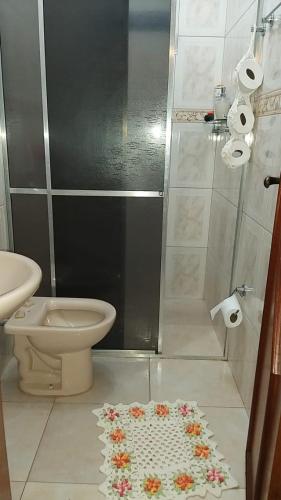a bathroom with a toilet and a shower with flowers on the floor at Casa de temporada em Aruanã in Aruanã