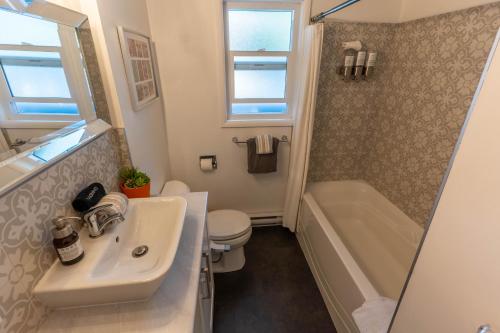 a bathroom with a sink and a toilet and a tub at Mid-Century Modern Apartment at Horner Park in Victoria