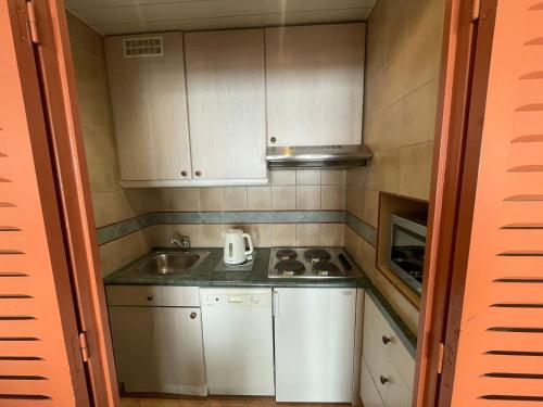 une petite cuisine avec des armoires blanches et un évier dans l'établissement Studio à 500m des pistes, balcon exposé sud, Wifi, animaux admis - FR-1-449-16, à Tignes