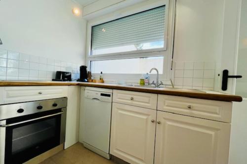 d'une cuisine avec des placards blancs, une fenêtre et un évier. dans l'établissement Bright T2 in the city center - La Rochelle, à La Rochelle