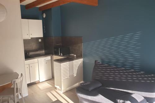 une cuisine avec un canapé et un mur bleu dans l'établissement CHARMANT Duplex 36 m avec Balcon proche de la MER, à La Rochelle