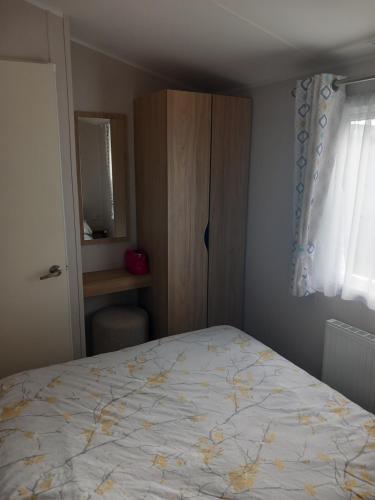 a bedroom with a bed and a cabinet and a window at Aquamarine Bythesea Porthcawl in Newton