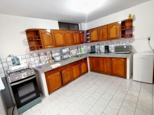 a kitchen with wooden cabinets and a white tiled floor at Departamento 28 in Piñas