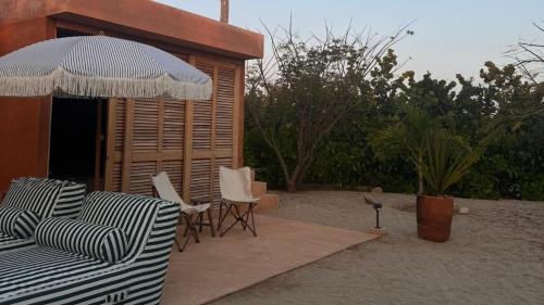 a patio with chairs and an umbrella and a building at Mazul Puerto Escondido in Tlachicón