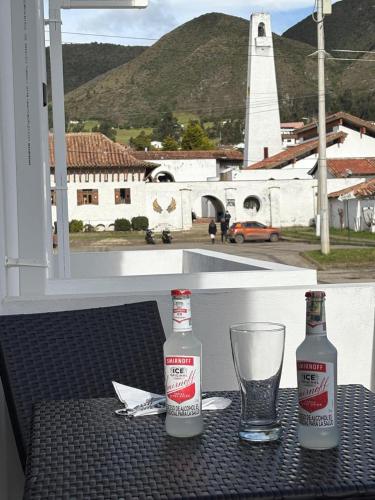 two bottles of coca cola and a glass on a table at Hospedaje Balcones de Guatavita in Guatavita