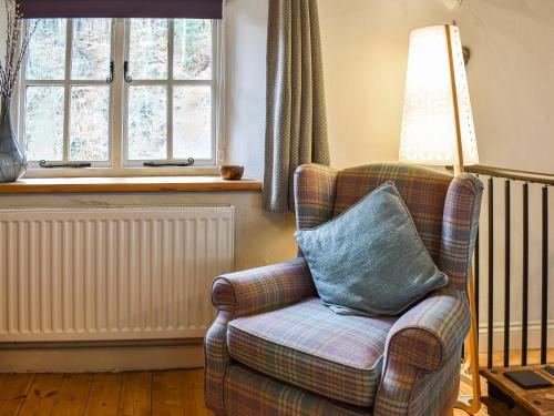 a chair with a blue pillow in a living room at Forge Cottage in Keswick