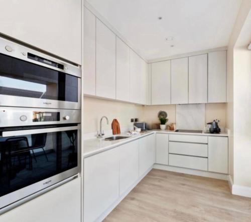 una cocina con armarios blancos y electrodomésticos de acero inoxidable en Luxury Seaview Apt in Dublin, en Dublín