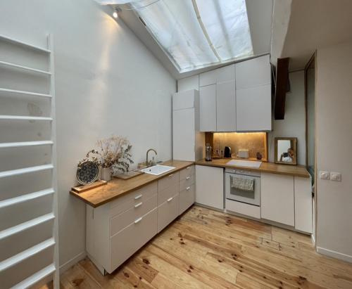 d'une cuisine avec des placards blancs et une lucarne. dans l'établissement Chambres Studio Eleusis-Paris, à Paris