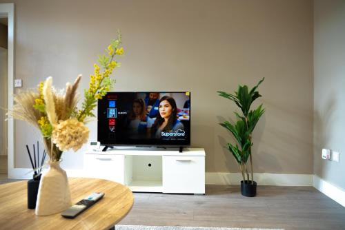 a living room with a flat screen tv on a white cabinet at Stylish Flat in Wolverhampton - Short and long Stay with Free Parking in Wolverhampton