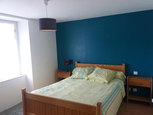 a bed in a bedroom with a blue wall at Gîtes du Café de la Poste in Le Buisson