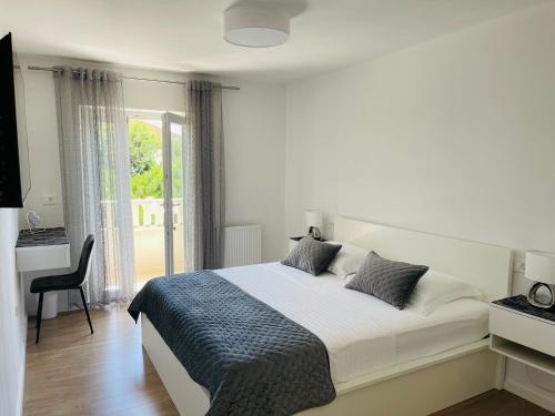 a white bedroom with a bed and a window at Villa Tajnikov in Hvar