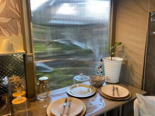 a table with plates and utensils and a window at African Paradise - Garden Glamping - Outdoor Shower in Benoni