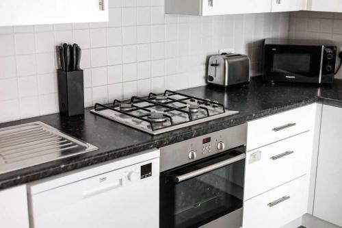 a kitchen with a stove top and a microwave at Castle Lanes - Minutes from Poole Quay, Poole Town Location in Poole