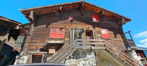 an old wooden house with red doors and stairs at Chalet Bernadette in Mörel
