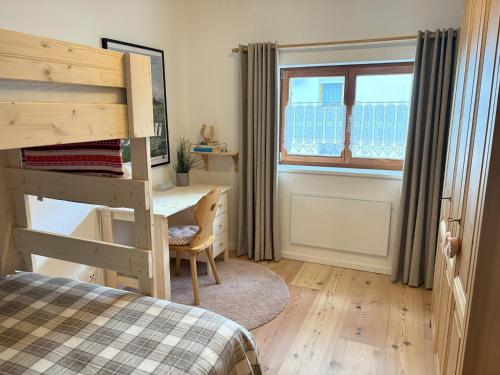 a bedroom with a bed and a desk and a window at Alpen family apartment Bergfreunde near skilift and golf course in Bad Kleinkirchheim