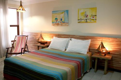 a bedroom with a bed with two chairs and two lamps at Pousada Manga Rosa Beira Mar in Natal
