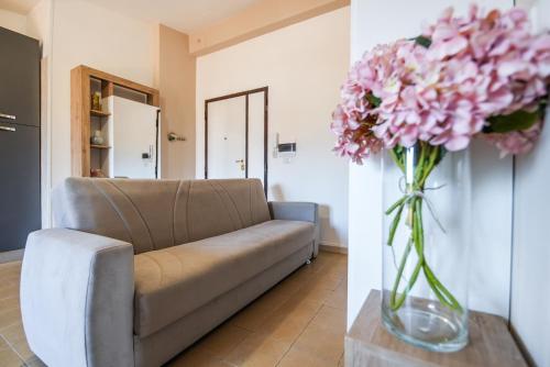 a living room with a couch and a vase of pink flowers at My Toy Holiday Pompei in Pompei
