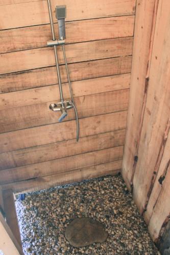 a shower in a wooden wall with a gravel floor at Outsidersi Campsite 