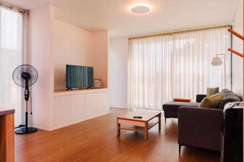 a living room with a couch and a tv at Galé T3 in Caloura