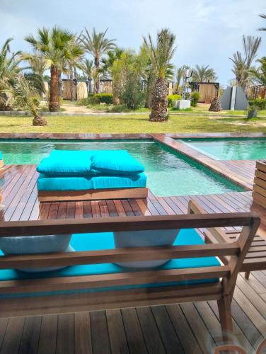 a pool with a wooden deck and a table with blue pillows at Sentido Marillia Resort & Spa in Hammamet