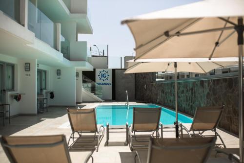a pool with chairs and umbrellas next to a building at IG Nachosol Atlantic & Yaizasol by Servatur - Adults Only in Puerto Rico de Gran Canaria